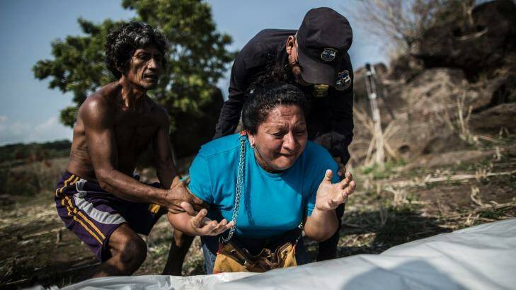 A woman mourns over the body of her brother, found in a clandestine grave, in a rural area of El Salvador.  Photo: Manu Brabo