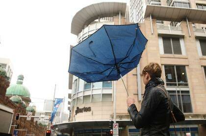 A woman walks in the CBD with a broken umbrella. Photo: Brendon Thorne
