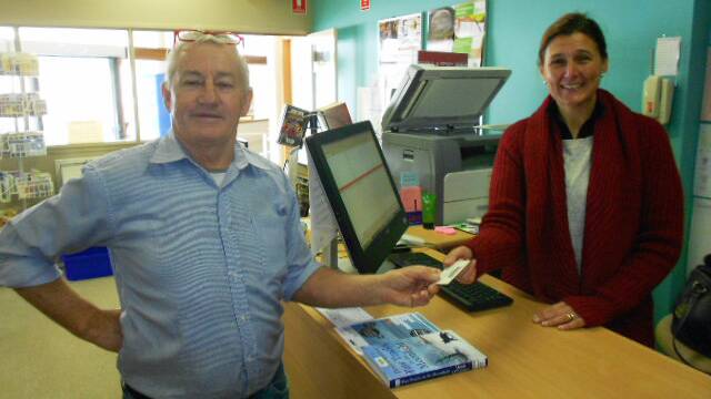 Allan Symons, now a patron of the library, borrowing books from new Library Officer, Rossanne Holmes. 