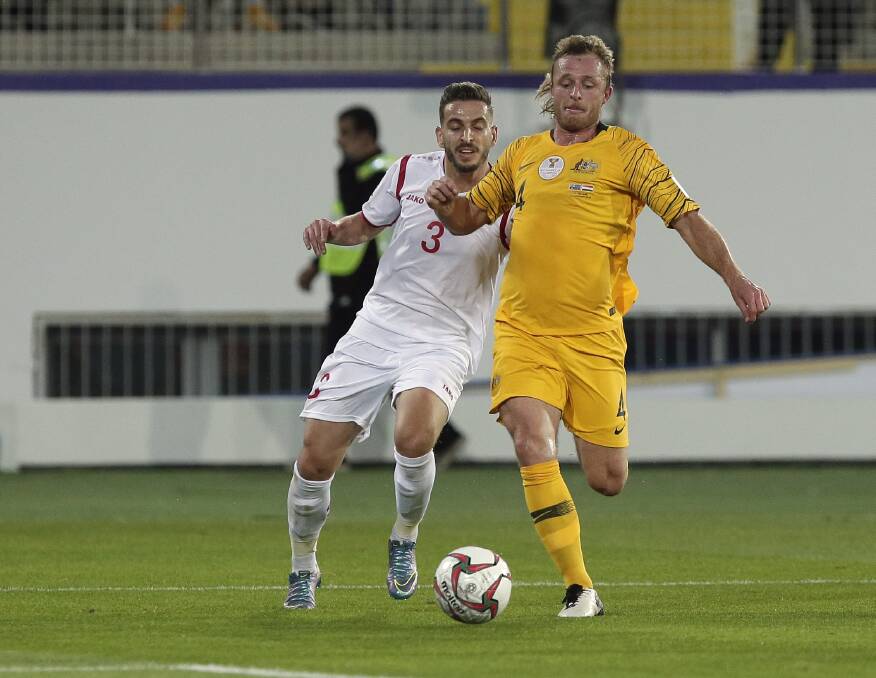 IN GREEN AND GOLD: Rhyan Grant beats a Syrian rival during the Socceroos' final pool game at the AFC Asian Cup. Photo: AP