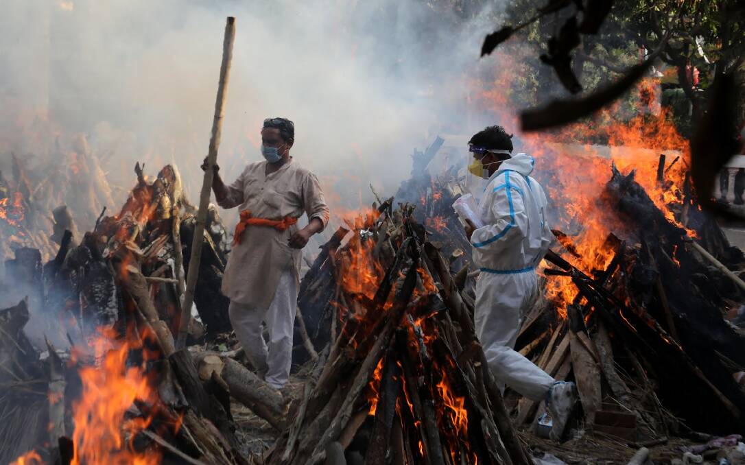 Tough times: Relatives stand next to the burning funeral pyres of those who died due to COVID-19 at Ghazipur cremation ground in New Delhi. Picture: Getty Images