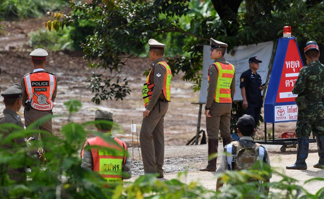 Thai police and military stand in position to guard the road for the ambulances. Picture: Kate Geraghty 